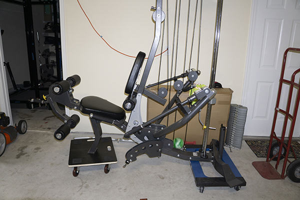 Photograph of Hoist Fitness V5 vertical gym after weight stack has been removed and rest of the intact gym is sitting on two furniture dollies.